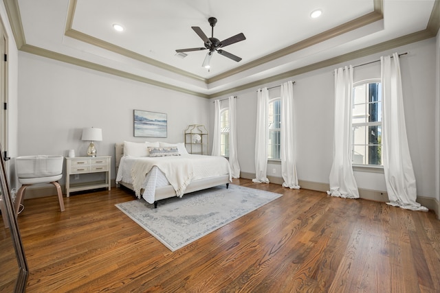 bedroom featuring crown molding, dark wood-type flooring, ceiling fan, and a tray ceiling