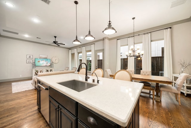 kitchen with an island with sink, sink, crown molding, and decorative light fixtures