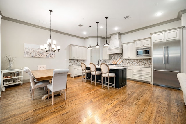 dining space with crown molding, sink, a chandelier, and light wood-type flooring