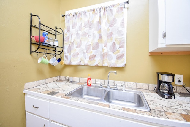 kitchen with white cabinets, tile counters, and sink