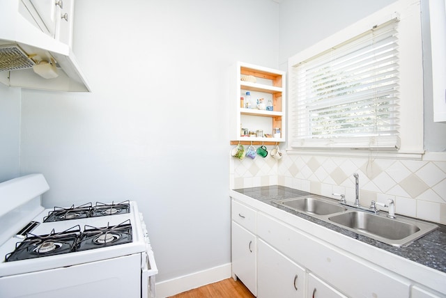 kitchen with white cabinets, sink, decorative backsplash, light wood-type flooring, and white range with gas cooktop