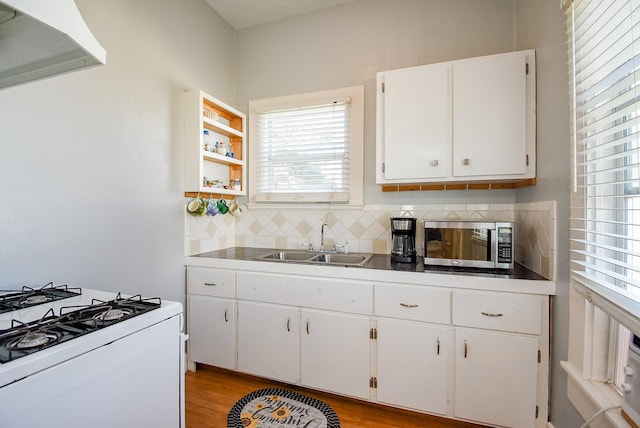 kitchen with white cabinets, white gas range oven, sink, light hardwood / wood-style flooring, and tasteful backsplash