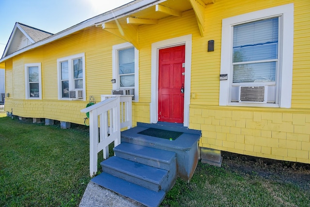 entrance to property featuring a yard and cooling unit