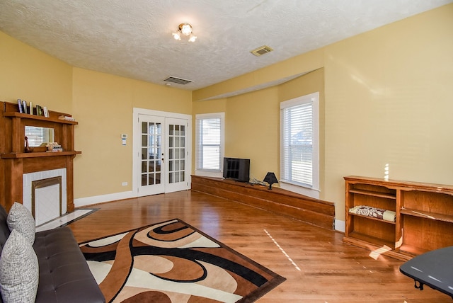 living room featuring french doors, wood-type flooring, and a textured ceiling