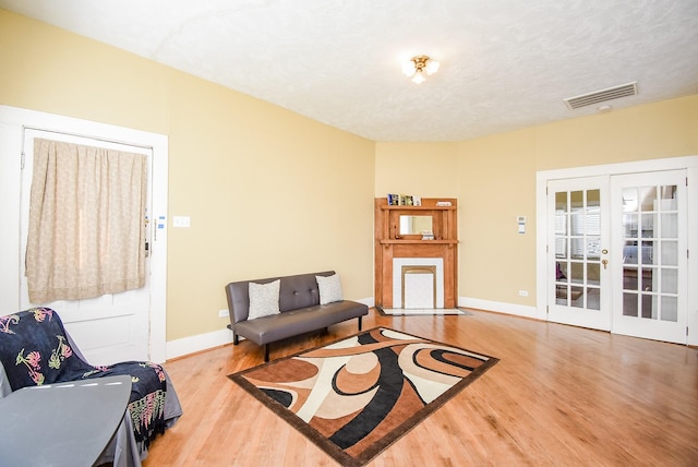 sitting room featuring french doors, wood-type flooring, and a textured ceiling