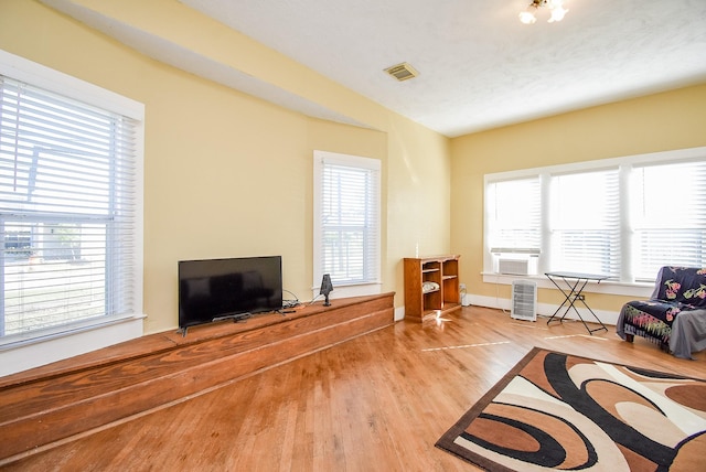 living room featuring light hardwood / wood-style flooring, plenty of natural light, and cooling unit