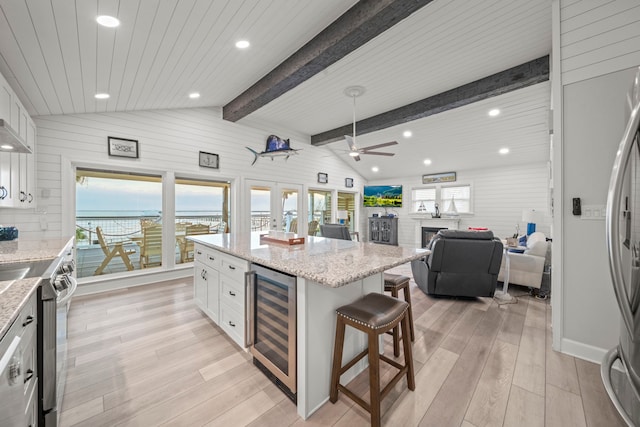 kitchen with white cabinetry, light stone counters, and beverage cooler