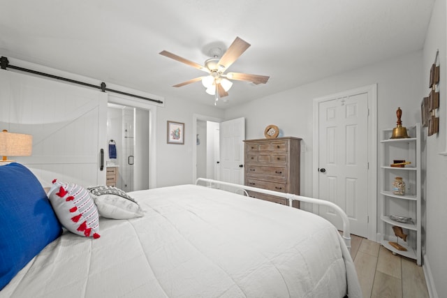 bedroom featuring ceiling fan, a barn door, and light hardwood / wood-style flooring