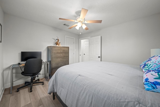 bedroom featuring ceiling fan, a textured ceiling, and light wood-type flooring