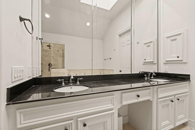 bathroom featuring a skylight, vanity, and tiled shower