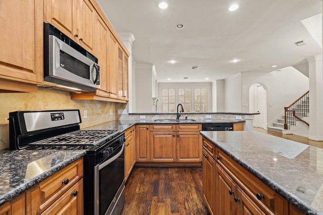 kitchen with sink, dark hardwood / wood-style flooring, dark stone counters, and appliances with stainless steel finishes