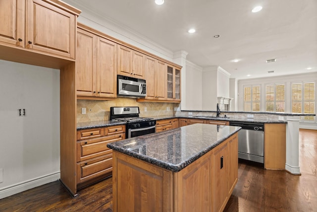 kitchen featuring a center island, dark stone countertops, kitchen peninsula, and appliances with stainless steel finishes