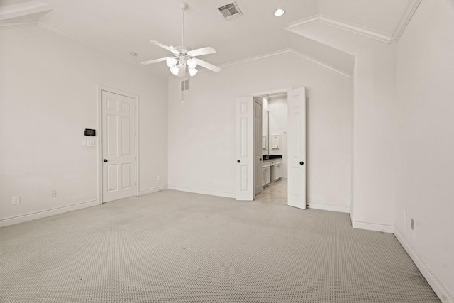 carpeted spare room with ceiling fan, vaulted ceiling, and ornamental molding