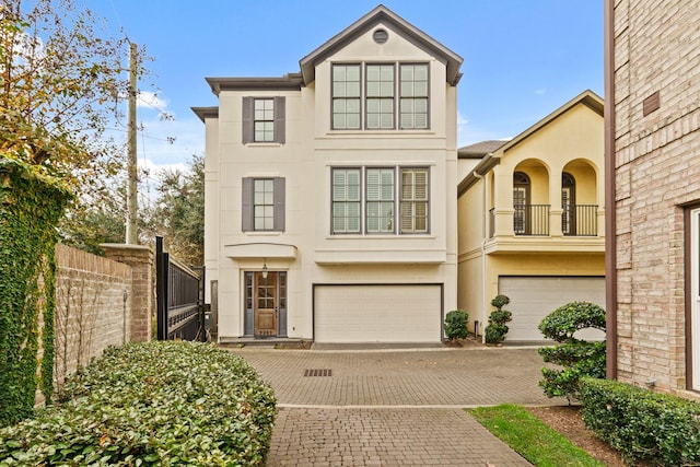 view of front of house featuring stucco siding, driveway, fence, an attached garage, and a balcony