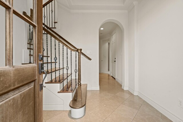 staircase with tile patterned floors and crown molding