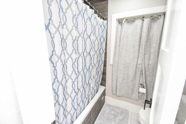 bathroom with tile patterned floors, shower / bath combination with curtain, and toilet