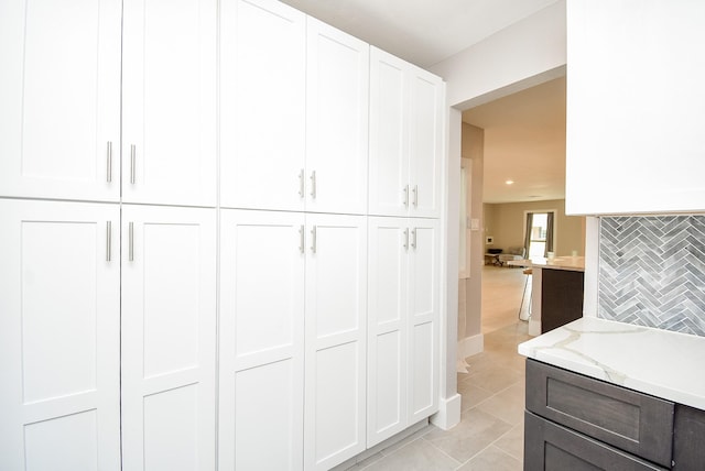 7618 Highmeadow Dr, Houston, TX 77063 - kitchen featuring white cabinets, light tile patterned floors, light stone countertops, and backsplash