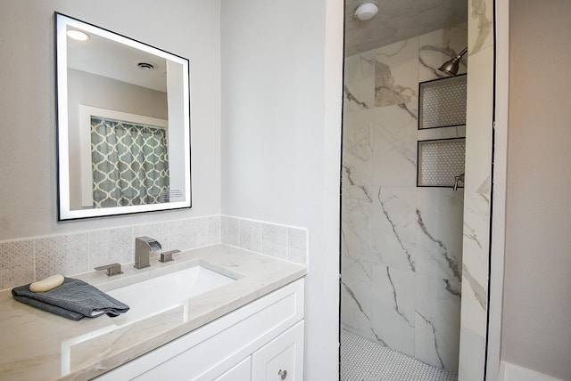 bathroom with a tile shower, vanity, and tile walls