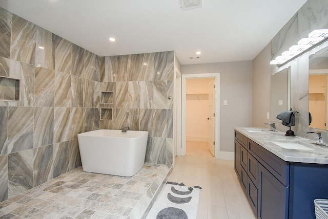 bathroom with vanity, tile walls, and a washtub