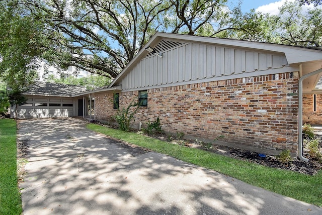 7618 Highmeadow Dr, Houston, TX 77063 - view of side of home featuring board and batten siding, brick siding, a garage, and driveway