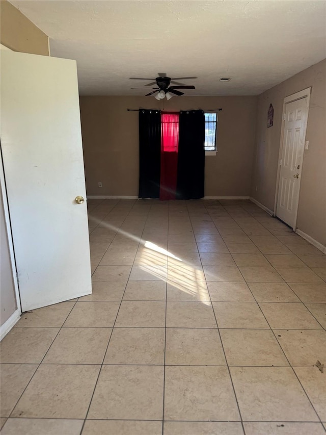 tiled spare room with ceiling fan