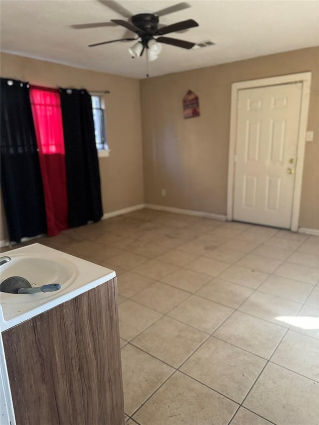 tiled spare room featuring ceiling fan and sink