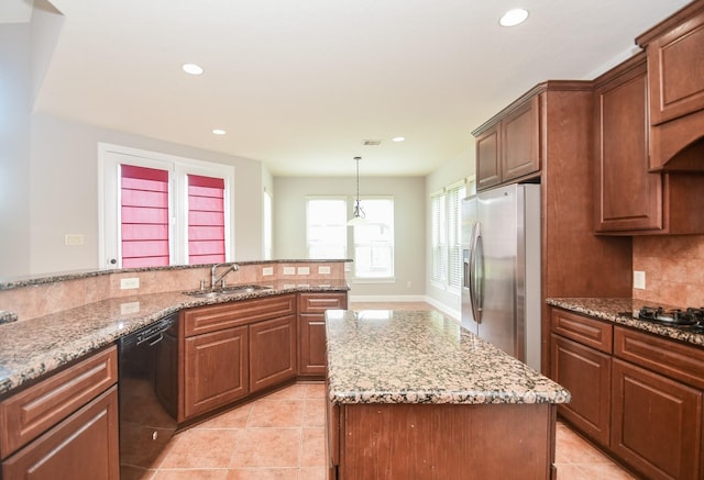 kitchen featuring light stone countertops, sink, hanging light fixtures, stainless steel appliances, and decorative backsplash