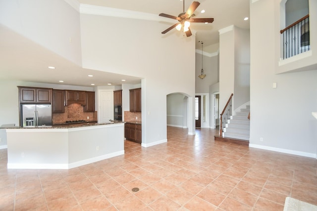 kitchen featuring decorative backsplash, stainless steel fridge, a towering ceiling, and light tile patterned floors