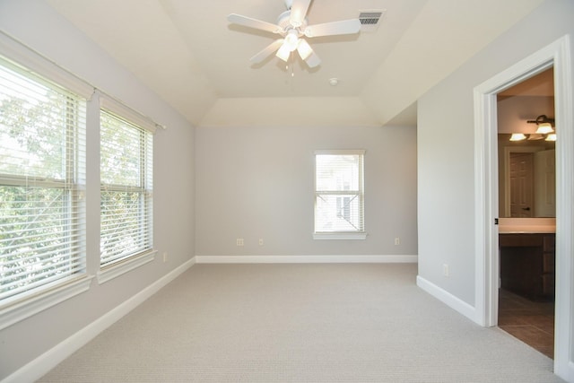 unfurnished bedroom with connected bathroom, ceiling fan, light colored carpet, and multiple windows