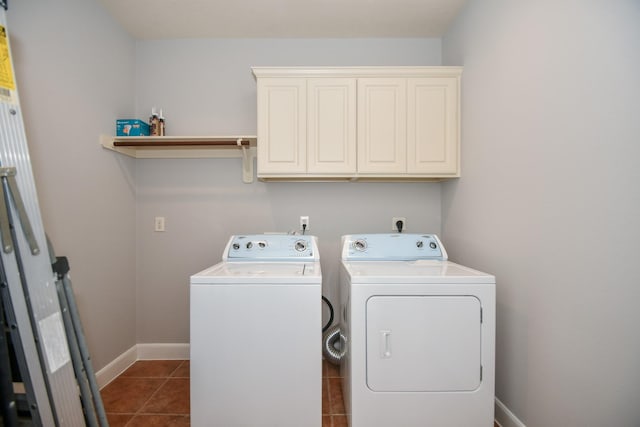 washroom featuring cabinets, washing machine and dryer, and dark tile patterned flooring