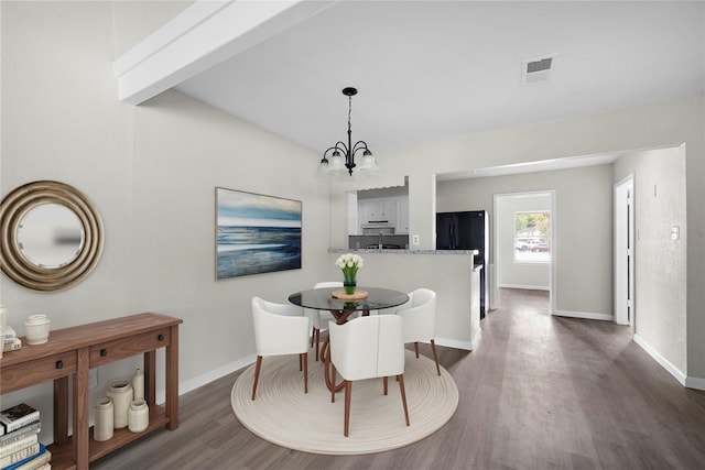 dining room with beamed ceiling, dark hardwood / wood-style flooring, and an inviting chandelier