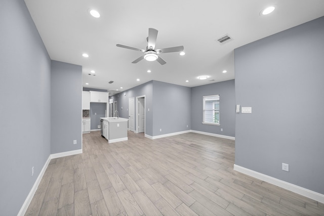 unfurnished living room with ceiling fan, sink, and light hardwood / wood-style floors