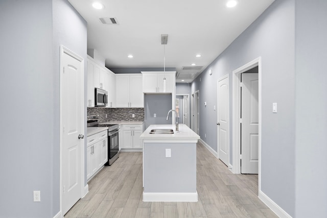 kitchen featuring appliances with stainless steel finishes, light wood-type flooring, a kitchen island with sink, sink, and white cabinets