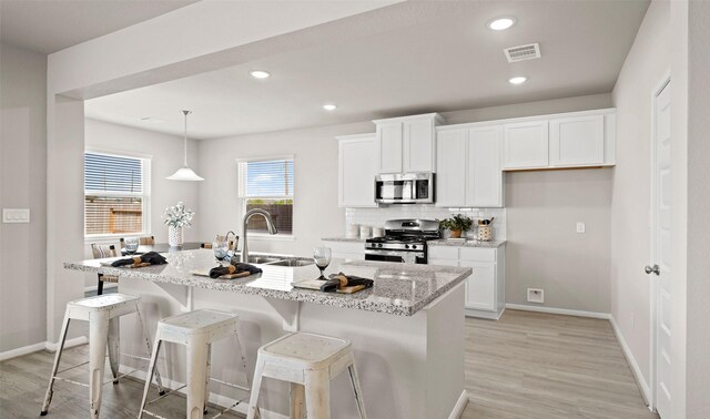 kitchen featuring a center island with sink, white cabinets, and appliances with stainless steel finishes