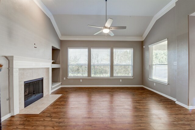 unfurnished living room featuring ceiling fan, crown molding, built in features, a fireplace, and hardwood / wood-style floors