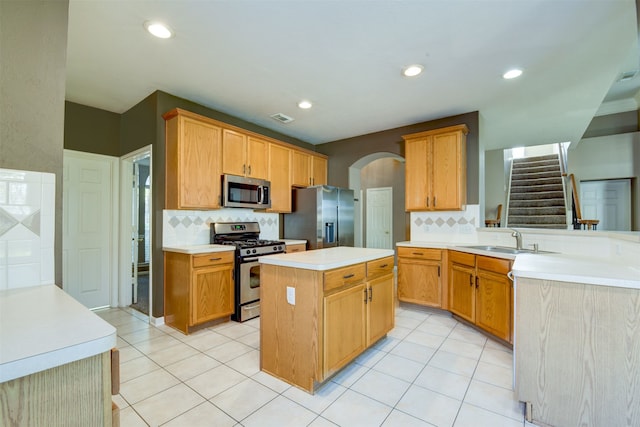 kitchen featuring sink, stainless steel appliances, a kitchen island, kitchen peninsula, and light tile patterned flooring