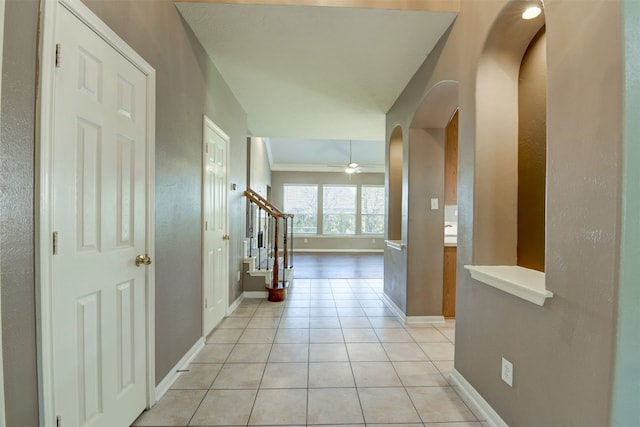 hallway with ornamental molding and light tile patterned flooring