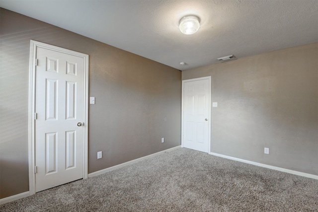 spare room featuring carpet floors and a textured ceiling