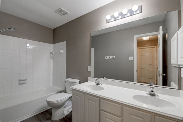 full bathroom featuring hardwood / wood-style floors, vanity, tiled shower / bath combo, and toilet