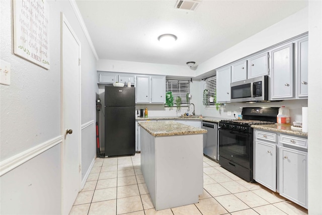 kitchen featuring sink, light stone counters, gray cabinets, a kitchen island, and black appliances