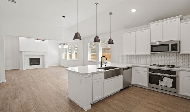 kitchen featuring kitchen peninsula, decorative light fixtures, white cabinetry, appliances with stainless steel finishes, and sink