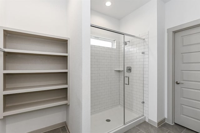 full bathroom with a shower stall, baseboards, and tile patterned flooring