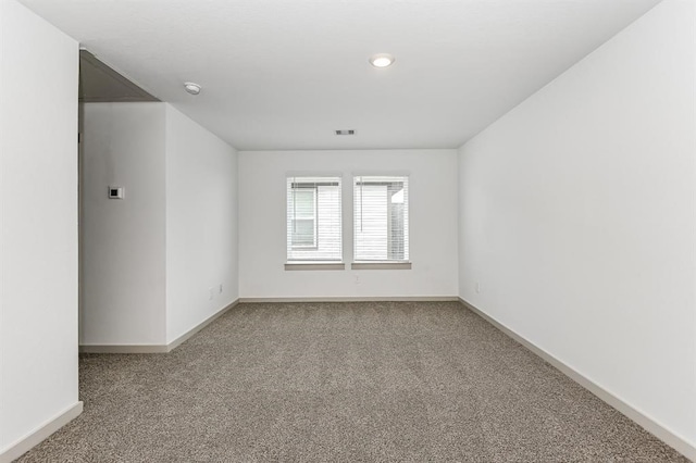 empty room with carpet, visible vents, and baseboards