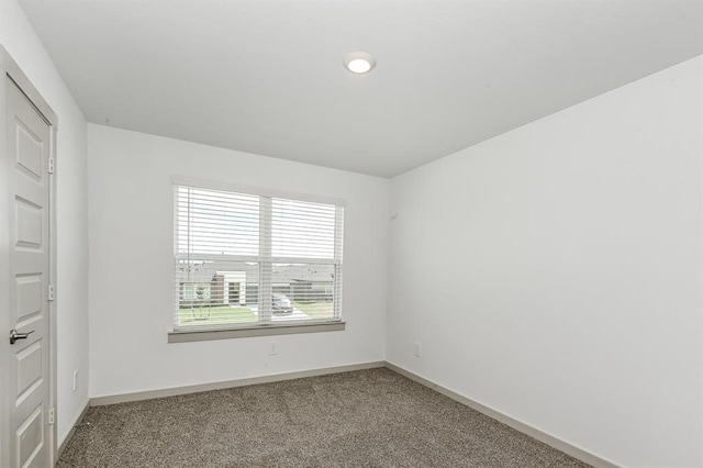 carpeted empty room featuring baseboards