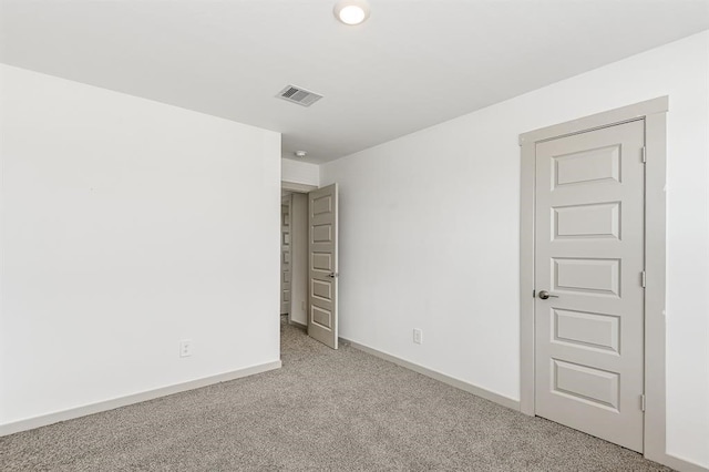 spare room featuring light carpet, visible vents, and baseboards