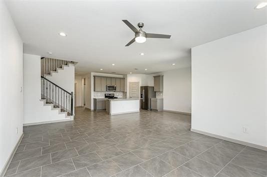 unfurnished living room featuring stairs, ceiling fan, baseboards, and recessed lighting