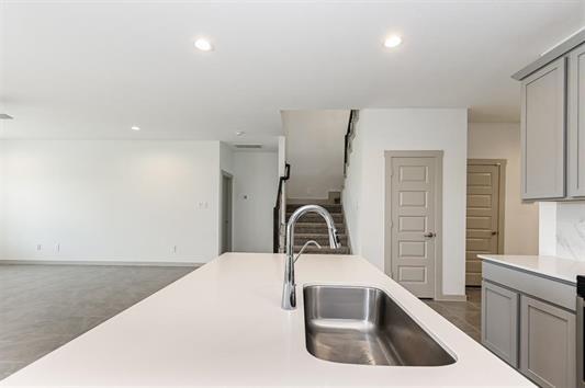 kitchen featuring open floor plan, light countertops, a sink, and gray cabinetry