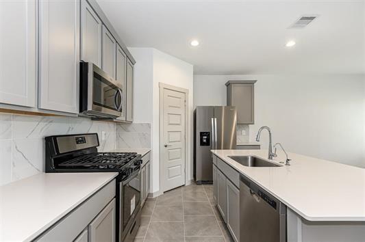 kitchen with light countertops, visible vents, gray cabinetry, appliances with stainless steel finishes, and a sink