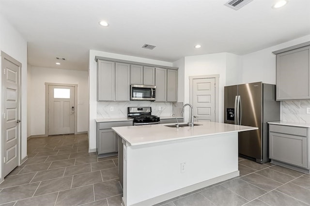 kitchen featuring visible vents, appliances with stainless steel finishes, a sink, and gray cabinetry