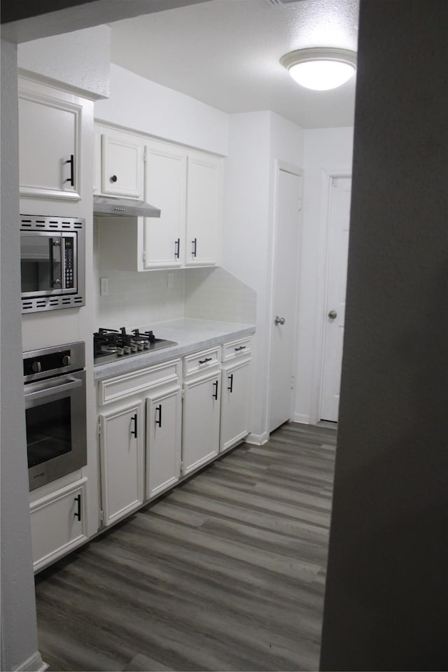 kitchen with white cabinetry, dark hardwood / wood-style flooring, stainless steel appliances, and ventilation hood